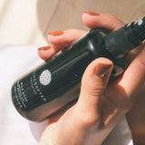 Hand holding a black bottle labeled 'Wildcrates' with a blurred background