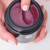 Person holding a jar of Wildcraft Organics product with a close-up of the cream.
