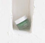 Green jar with white lid labeled 'Wildcrafted' on a textured white background