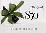 Gift card with a bottle of Wildcrafted Organics product and a green bow on a white background.