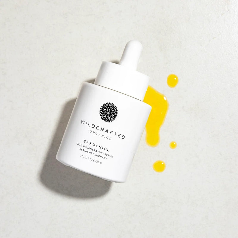 White skincare serum bottle with yellow droplets on a light gray background