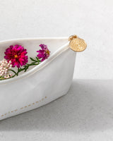 White dish with flowers and a gold decorative element on a light gray background