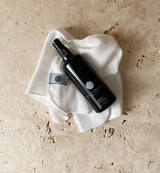 Black spray bottle on a white cloth with a beige background
