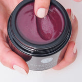 Person holding a jar of Wildcraft Organics product with a close-up of the cream.